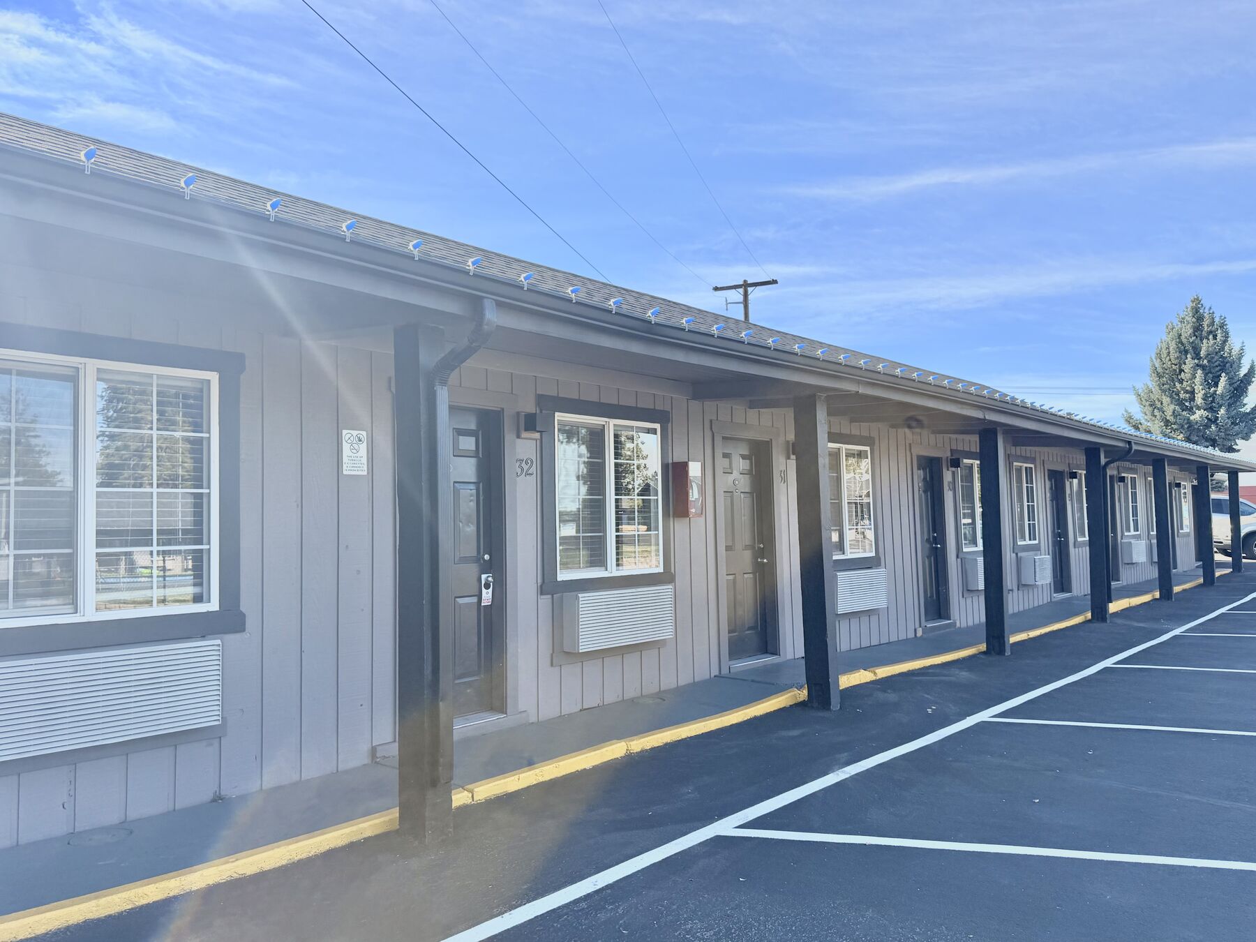 Long view of a guest room building with windows and doors facing the parking area