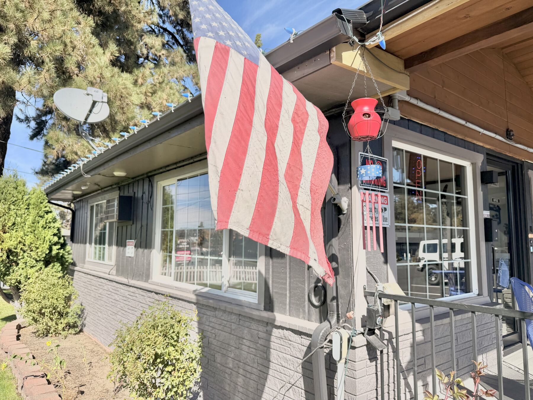 Front office entrance with an American flag, hanging flower basket, and windows onto the porch