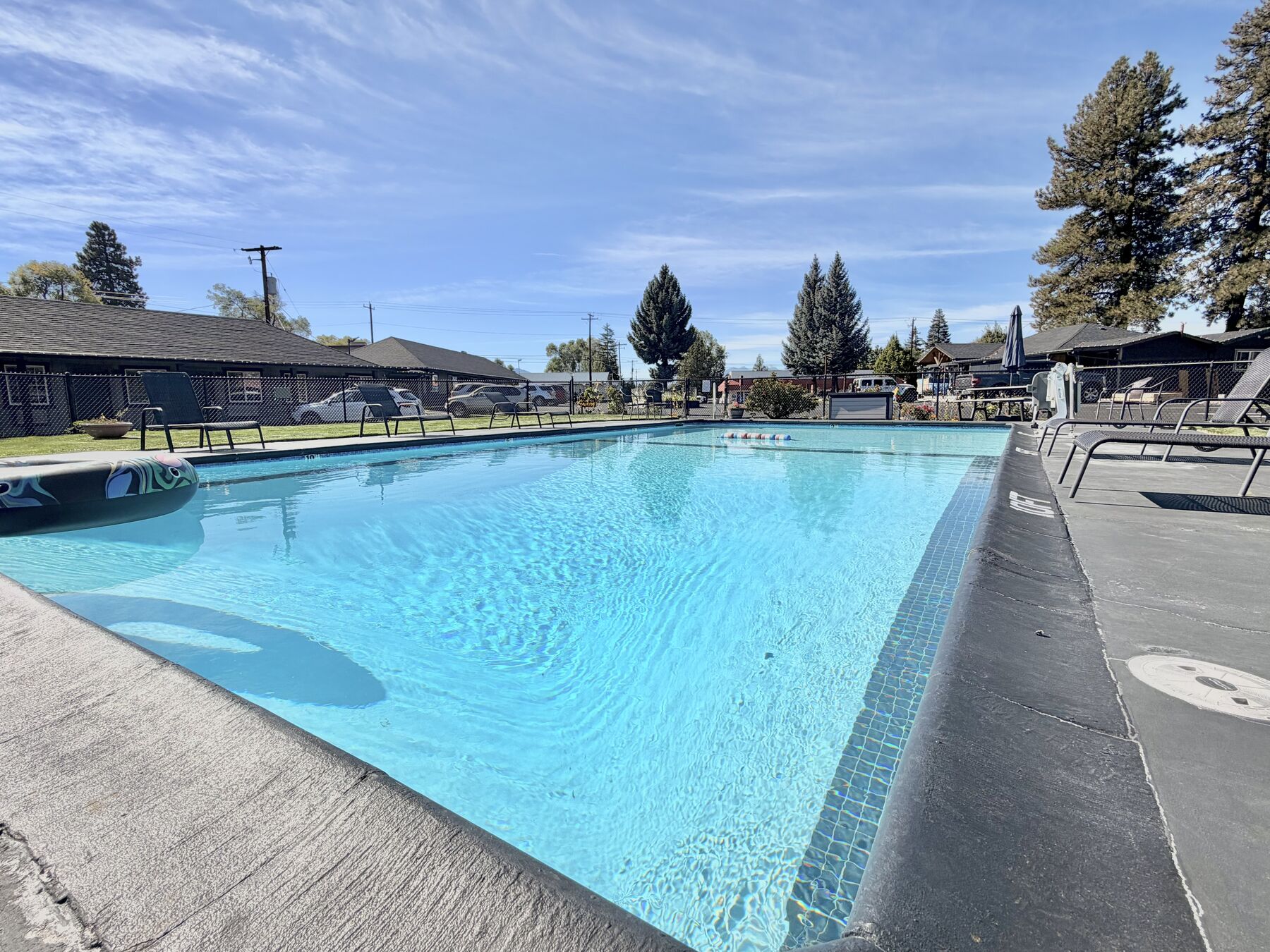 Heated outdoor pool with lounge chairs, the guest room buildings and tall pines beyond