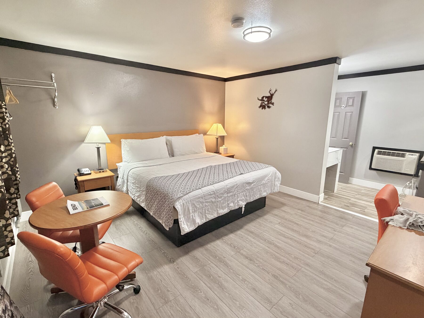 Bachelor King room with a king bed, bedside lamps, and a round table with orange chairs