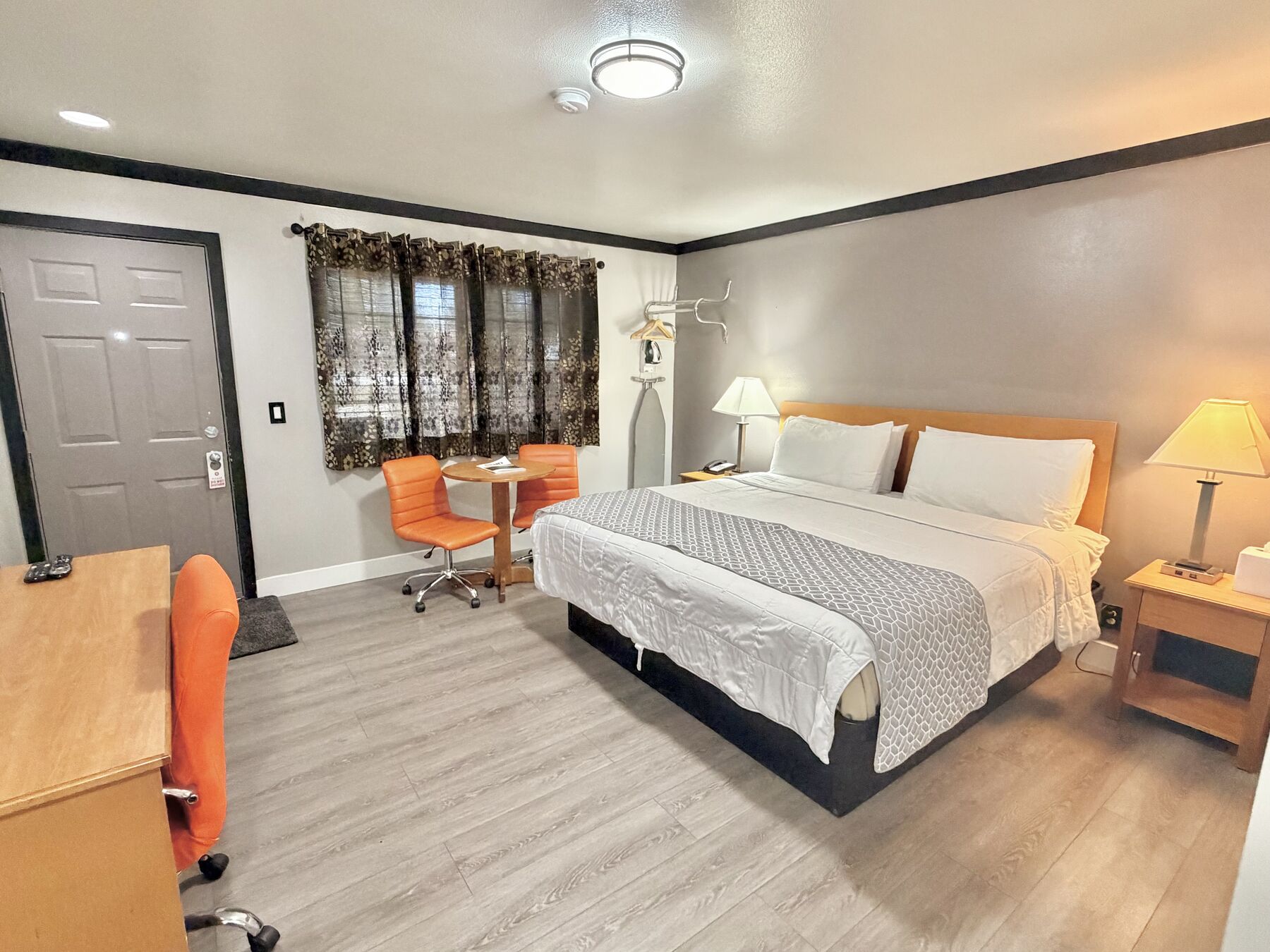 Bachelor King bed seen from the entry, with the curtained window, sitting area, and work desk