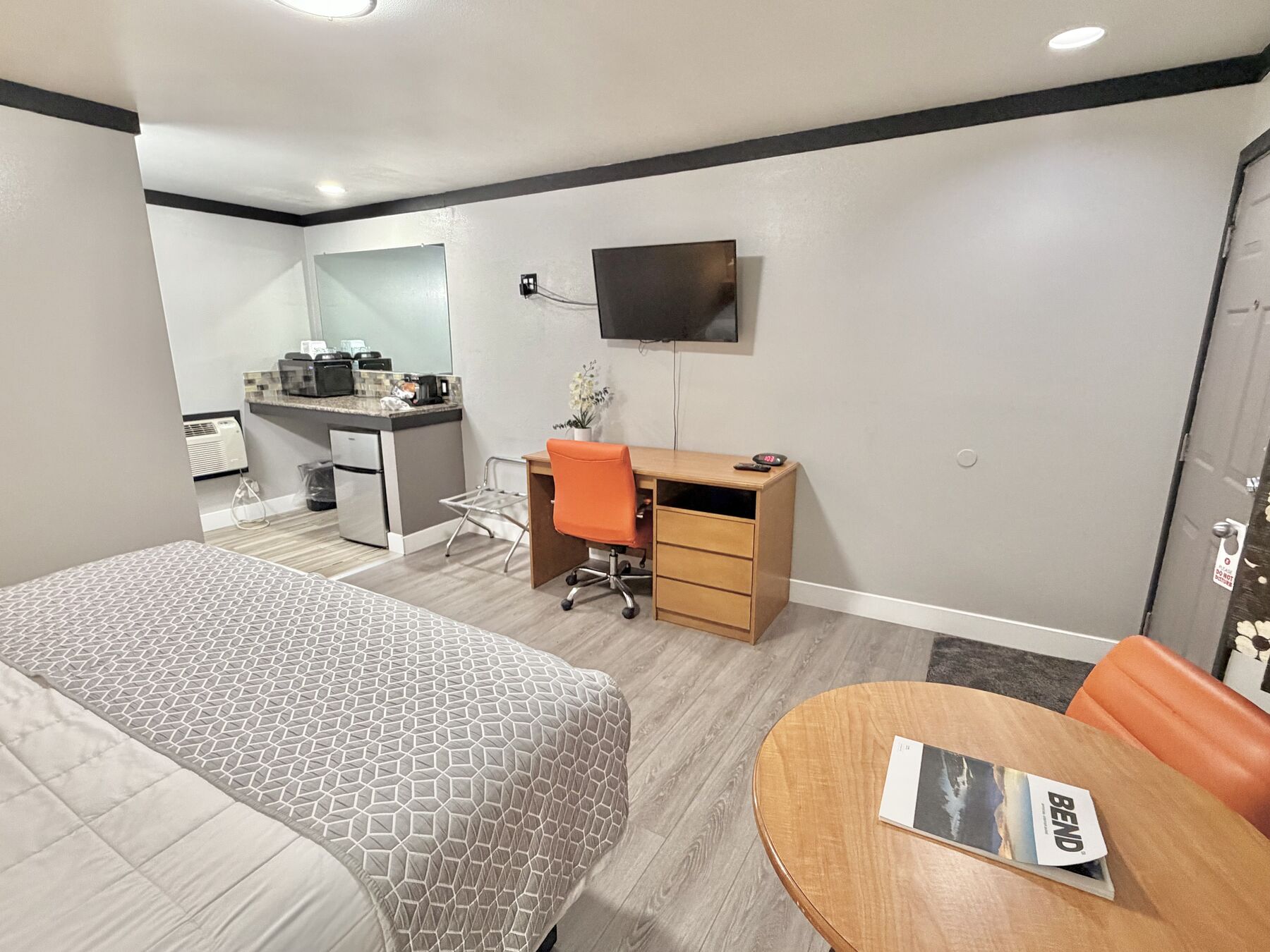 Bachelor King work desk with orange chair and wall-mounted TV beside the coffee and microwave counter