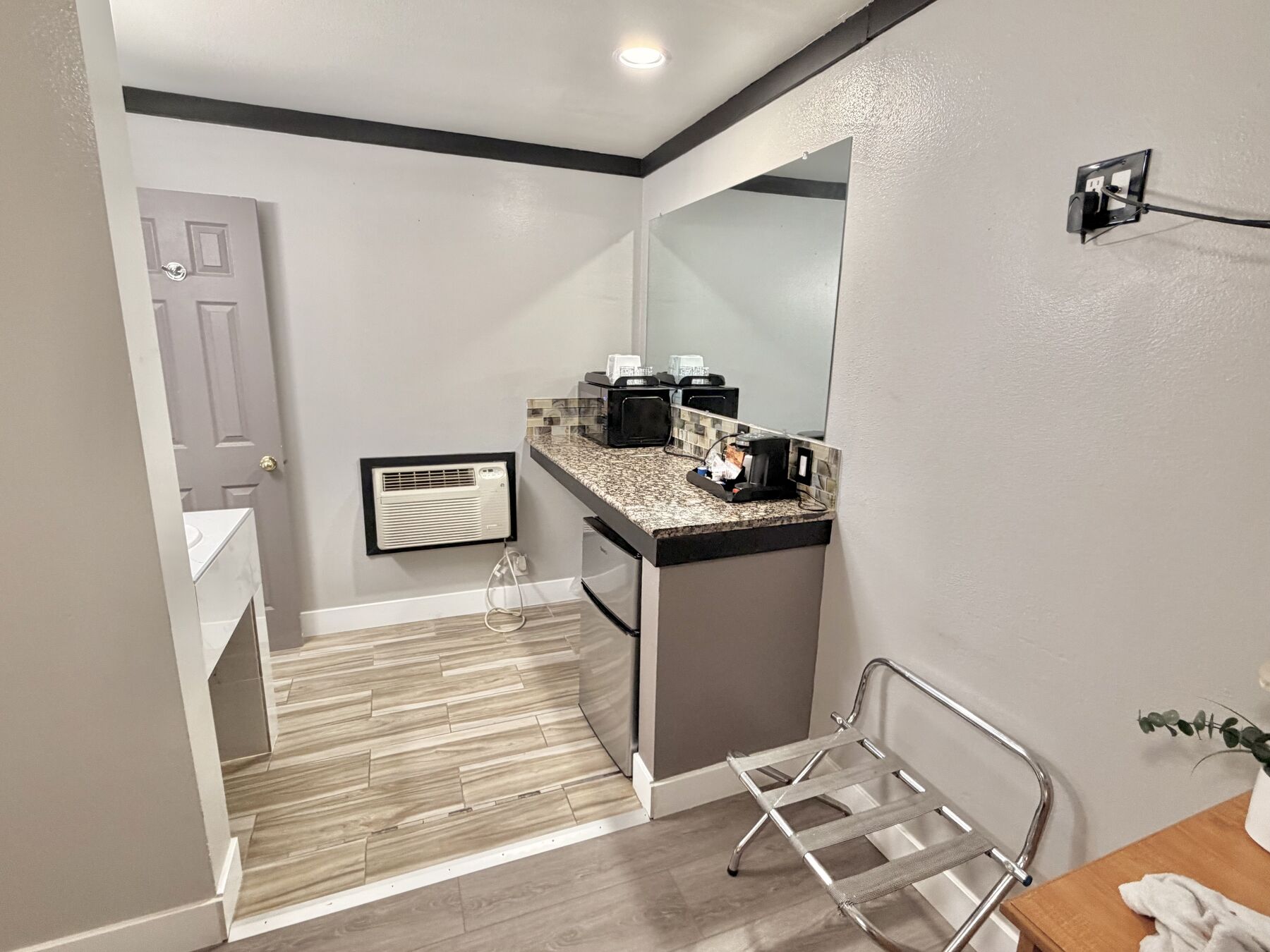 Bachelor King vanity area with granite counter, microwave, coffee maker, mirror, and luggage rack
