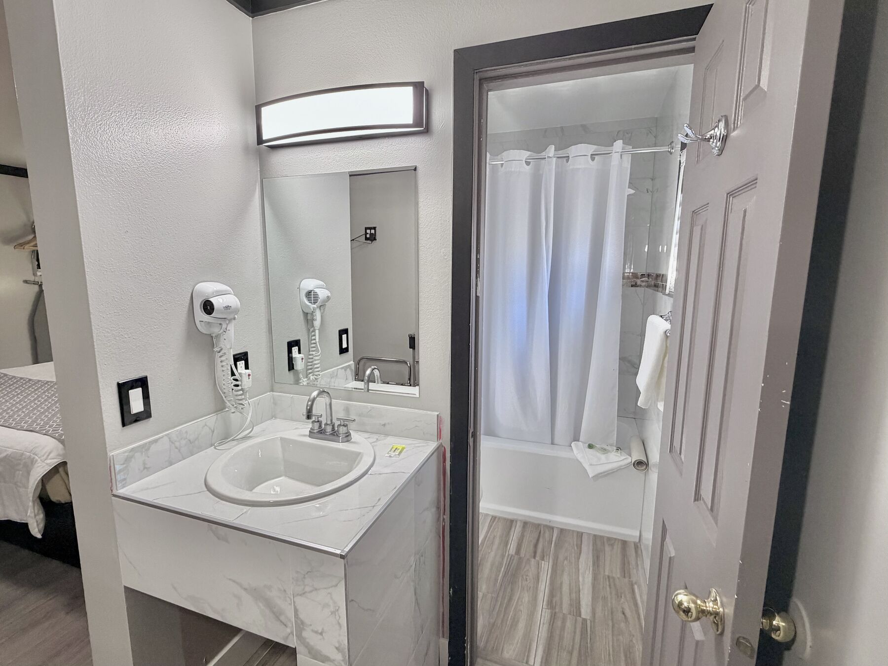 Bachelor King bathroom sink with lit mirror and hair dryer, with the shower beyond