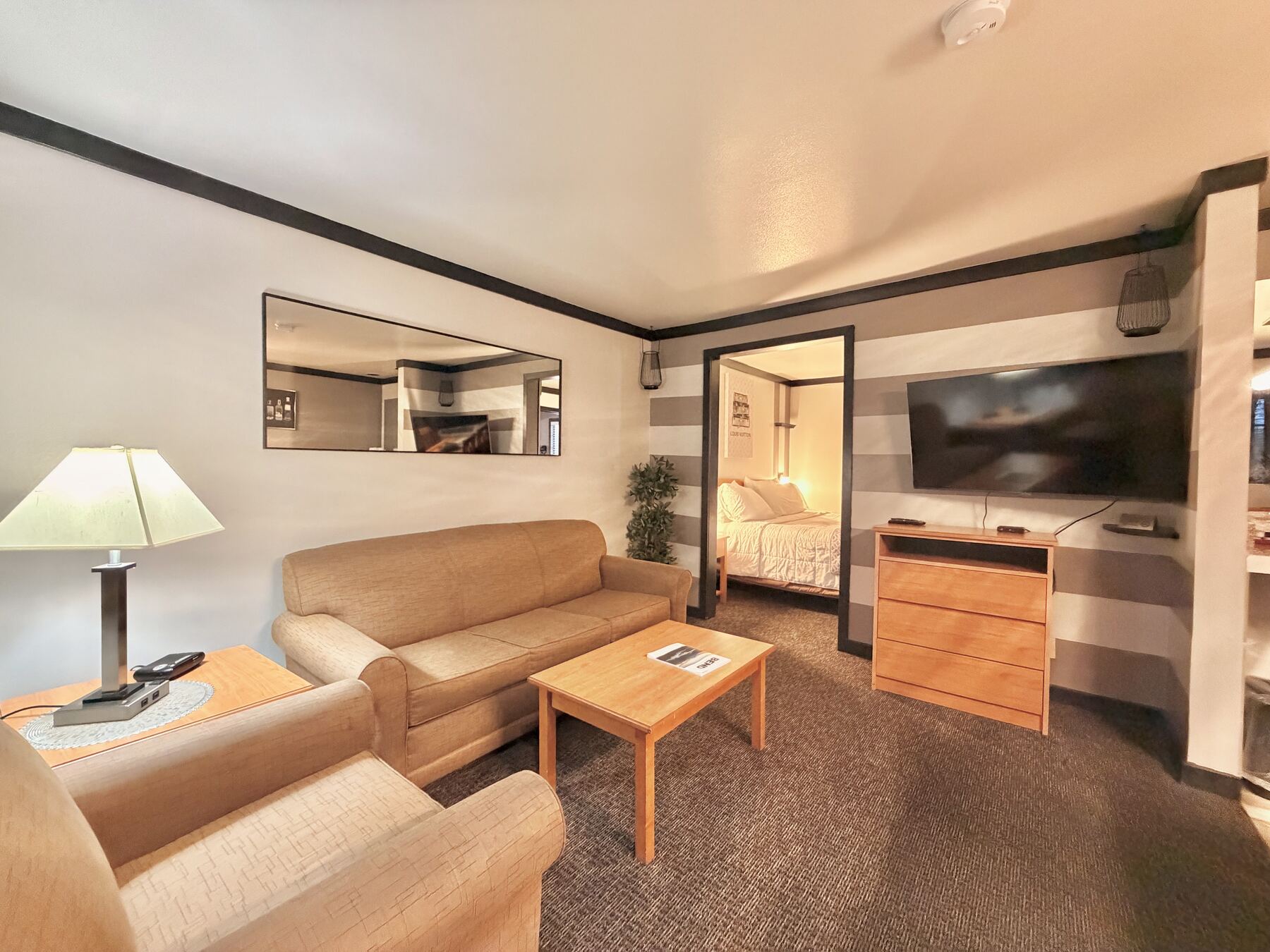 Broken Top King Spa Suite living room with a sofa, armchair, coffee table, and TV, with the bedroom beyond