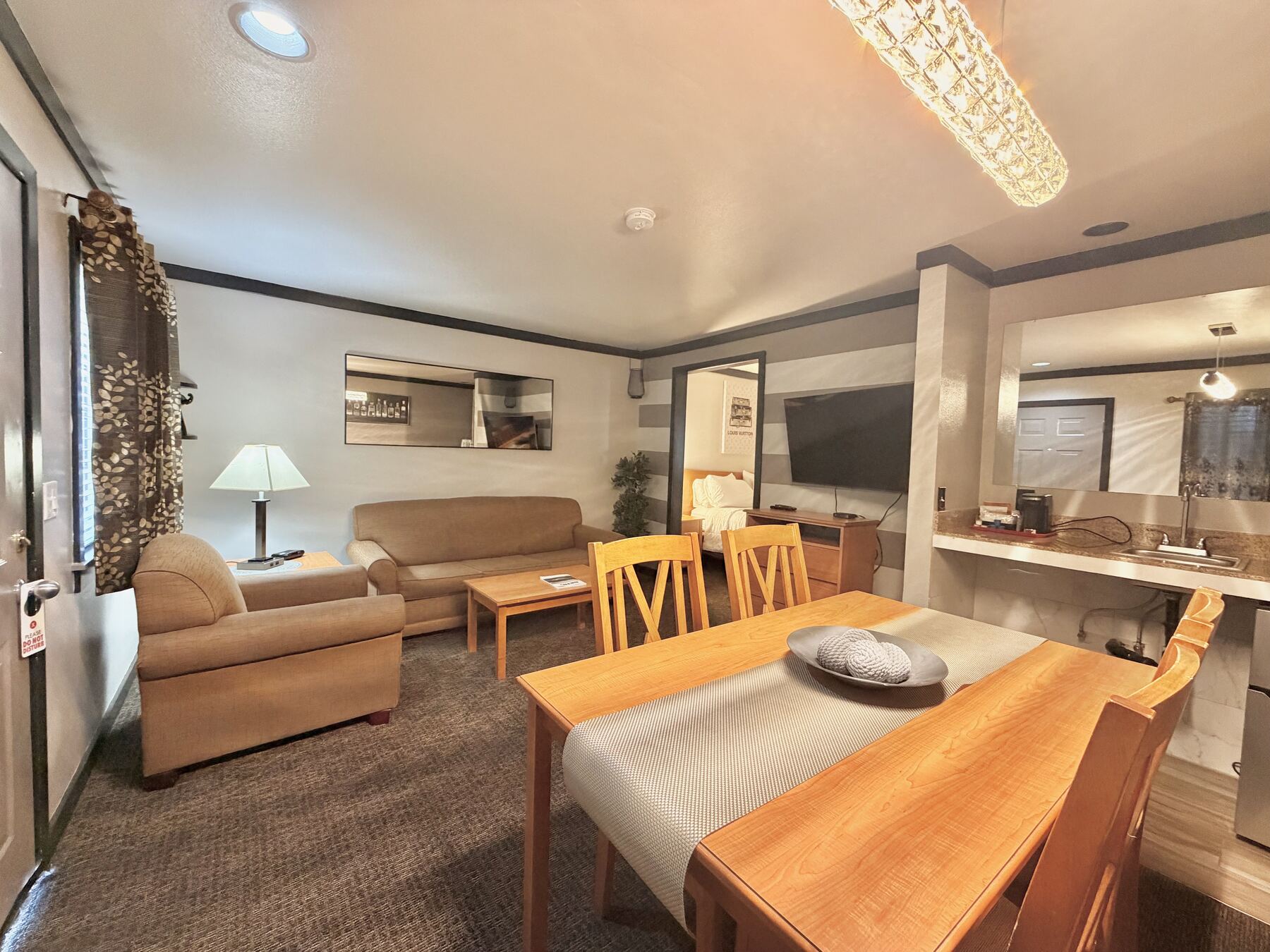 Broken Top King Spa Suite dining table seating four, with the sitting area and kitchenette counter beyond
