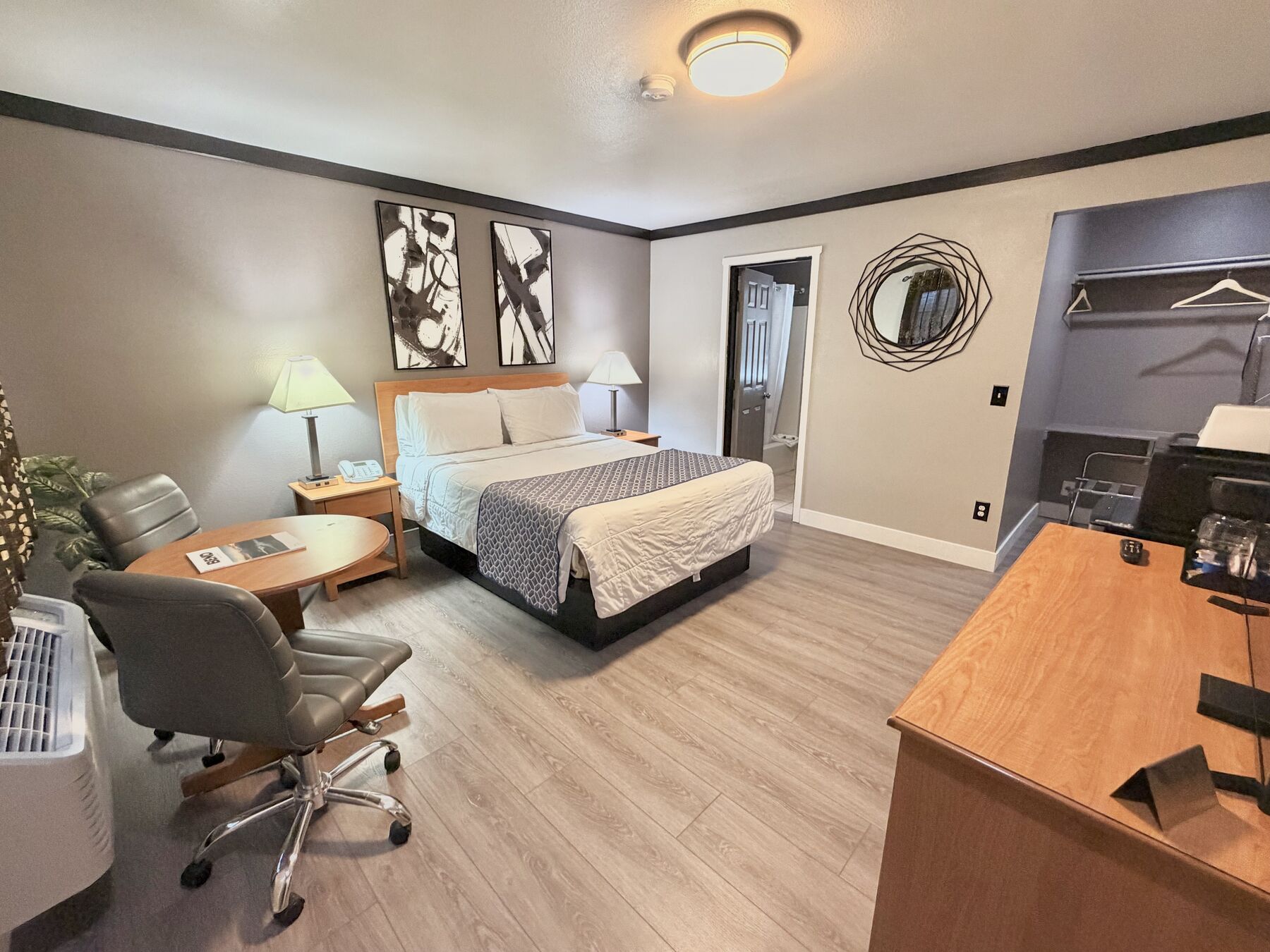 Cascade Queen room with a queen bed, abstract wall art, round table with chairs, desk, and open closet