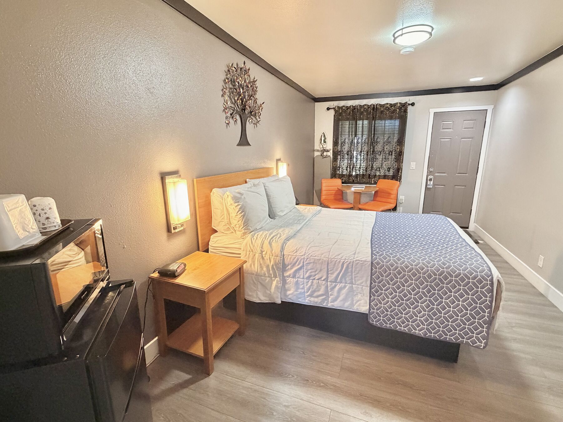 Cascade Queen bed seen from beside the microwave and mini fridge, with the sitting area and entry door beyond
