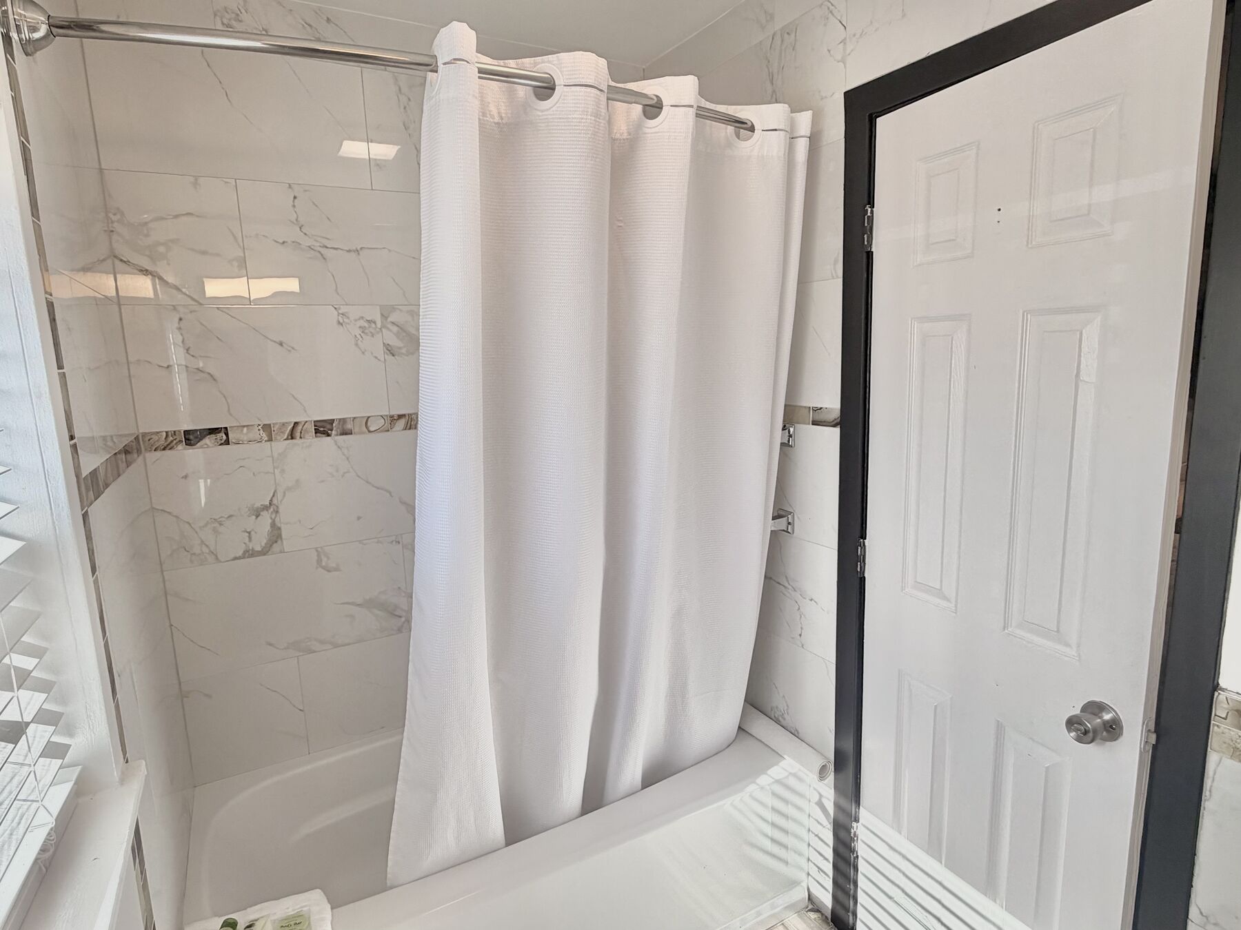 Deschutes Double Queen tub and shower with marble-look tile and a white curtain