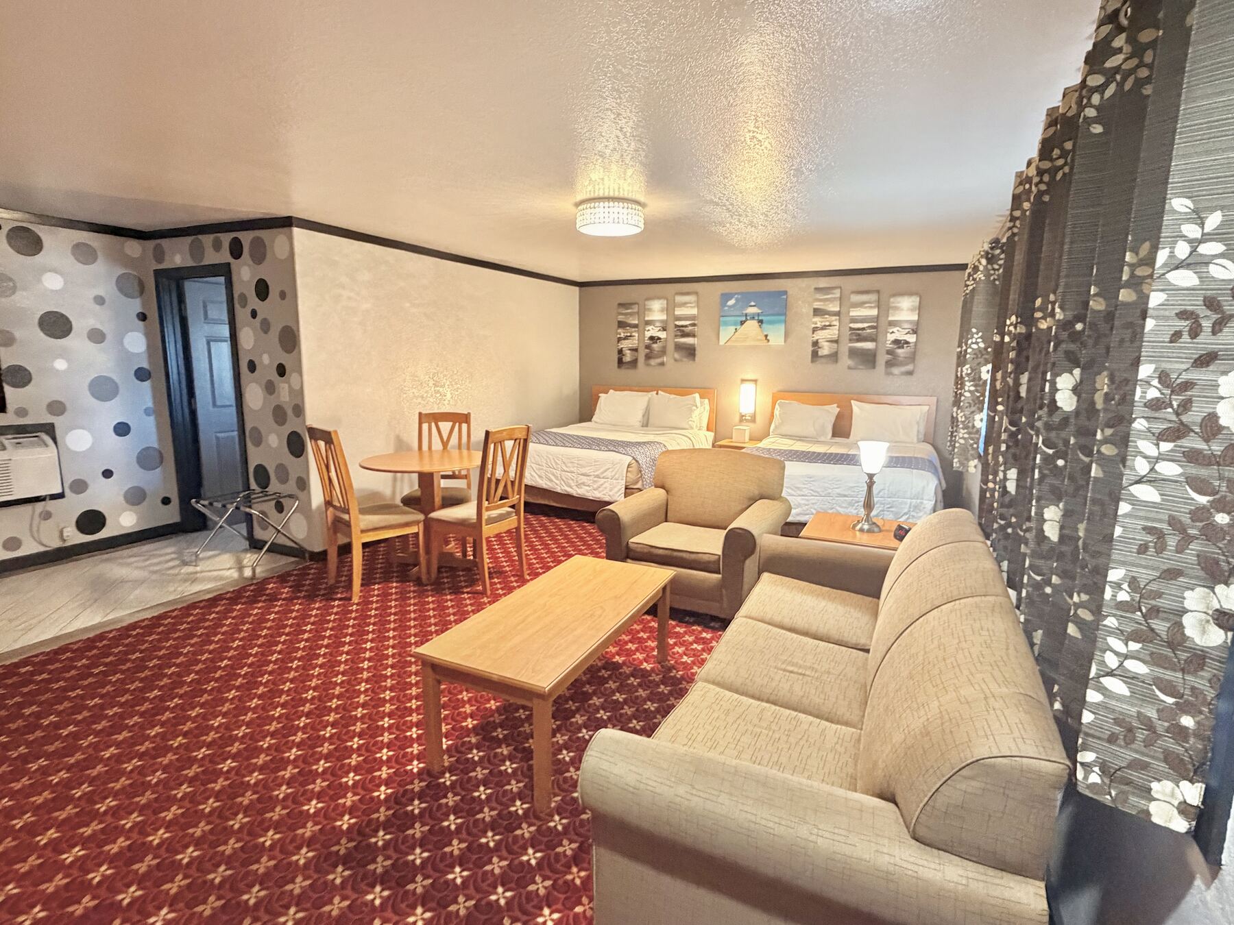 High Desert Deluxe Double Queen with two queen beds, a sofa, armchair, coffee table, and dining table in a spacious open room
