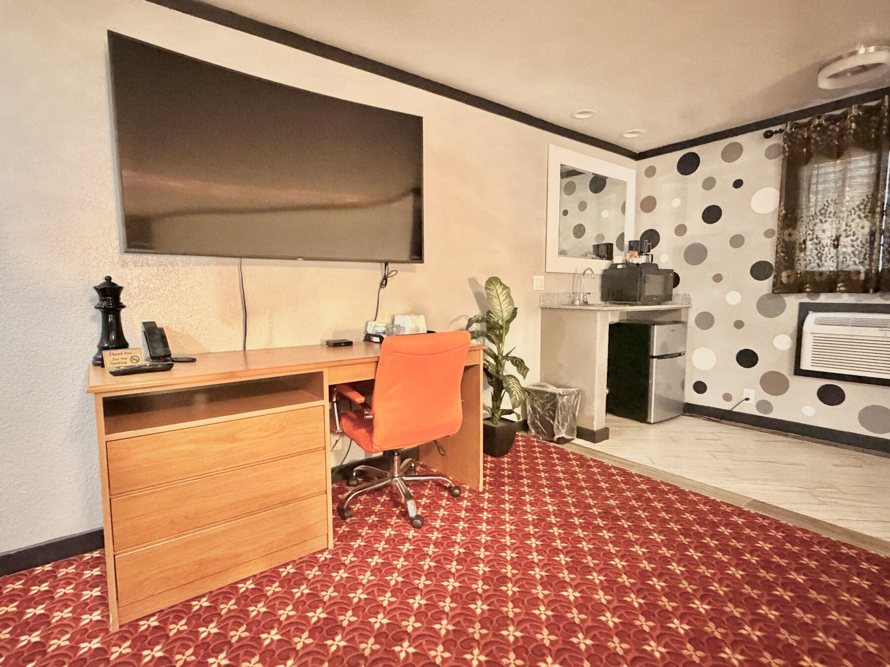 High Desert Deluxe Double Queen work desk with orange chair and large wall-mounted TV, with the wet bar beyond