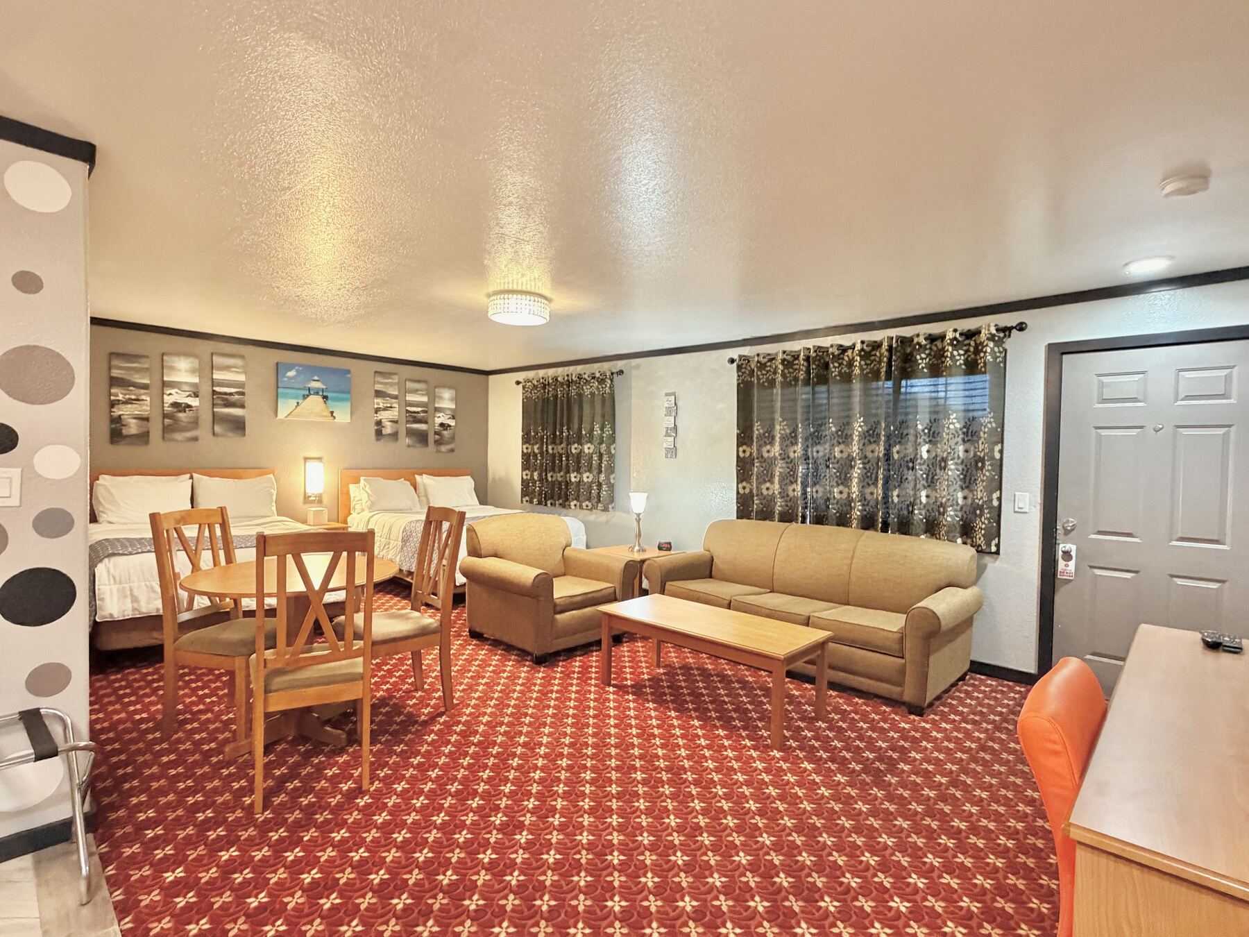 High Desert Deluxe Double Queen seen from the entry, with two queen beds, a dining table for four, and a sofa and armchair