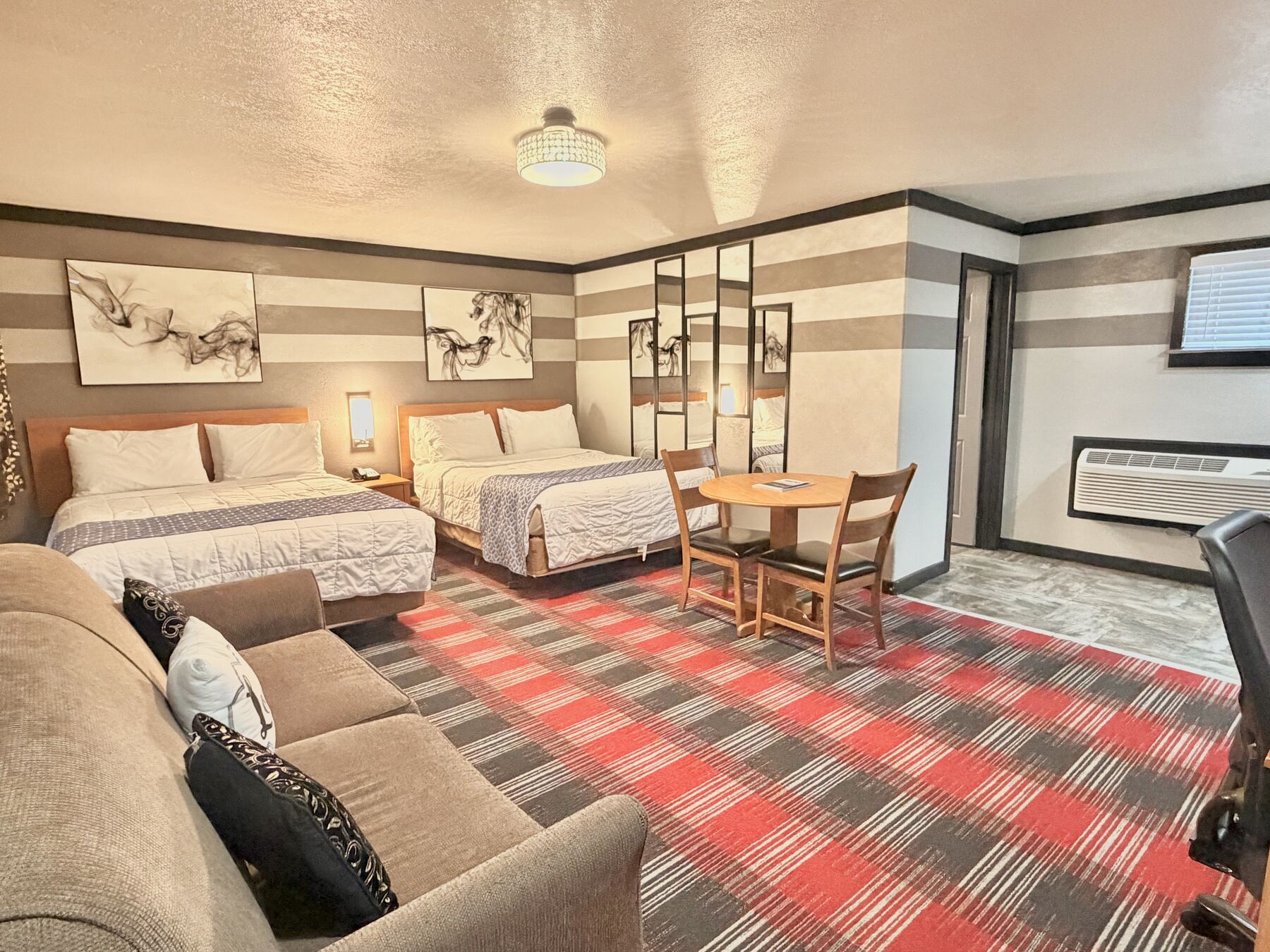 High Desert Deluxe Double Queen with two queen beds, a sofa, and a round table with chairs