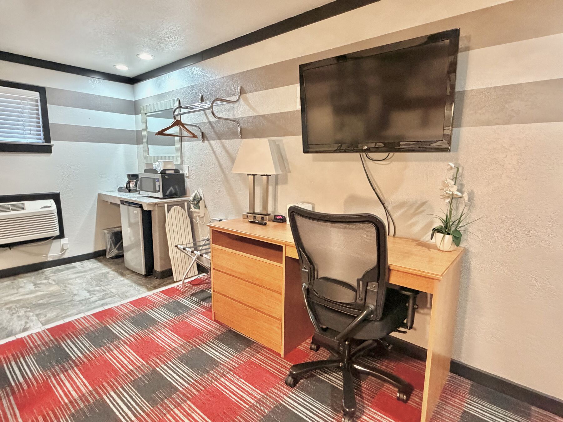 High Desert Deluxe Double Queen work desk with mesh chair, wall-mounted TV, and wet bar with microwave