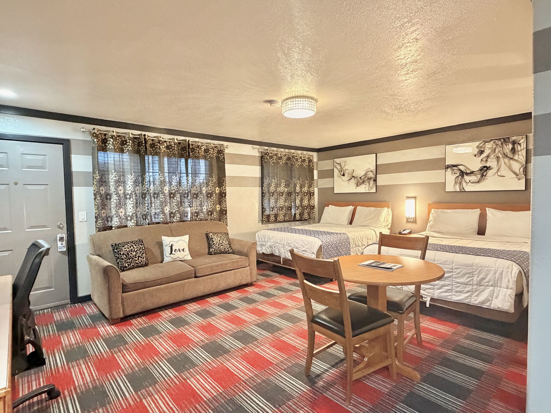High Desert Deluxe Double Queen two queen beds, sofa, and round table with chairs by the windows