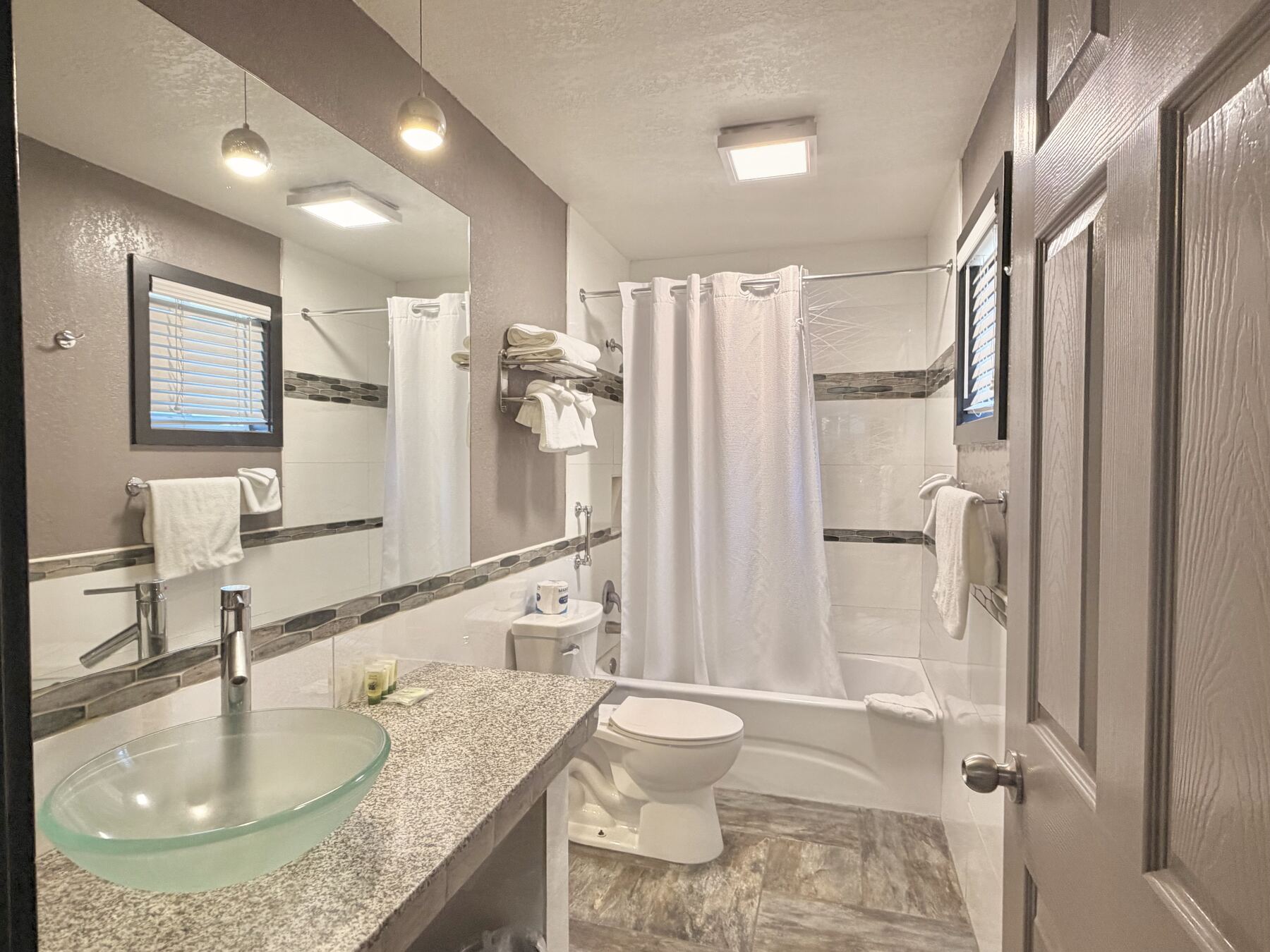 High Desert Deluxe Double Queen bathroom with a glass vessel sink, granite counter, and tiled tub and shower