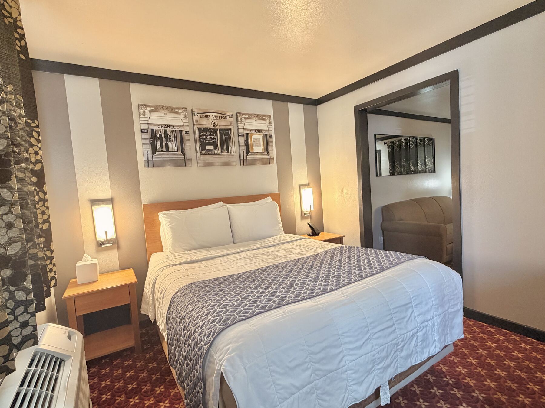 Sisters Queen Spa Suite bedroom with a queen bed, wall sconces, framed art, and a doorway to the living room