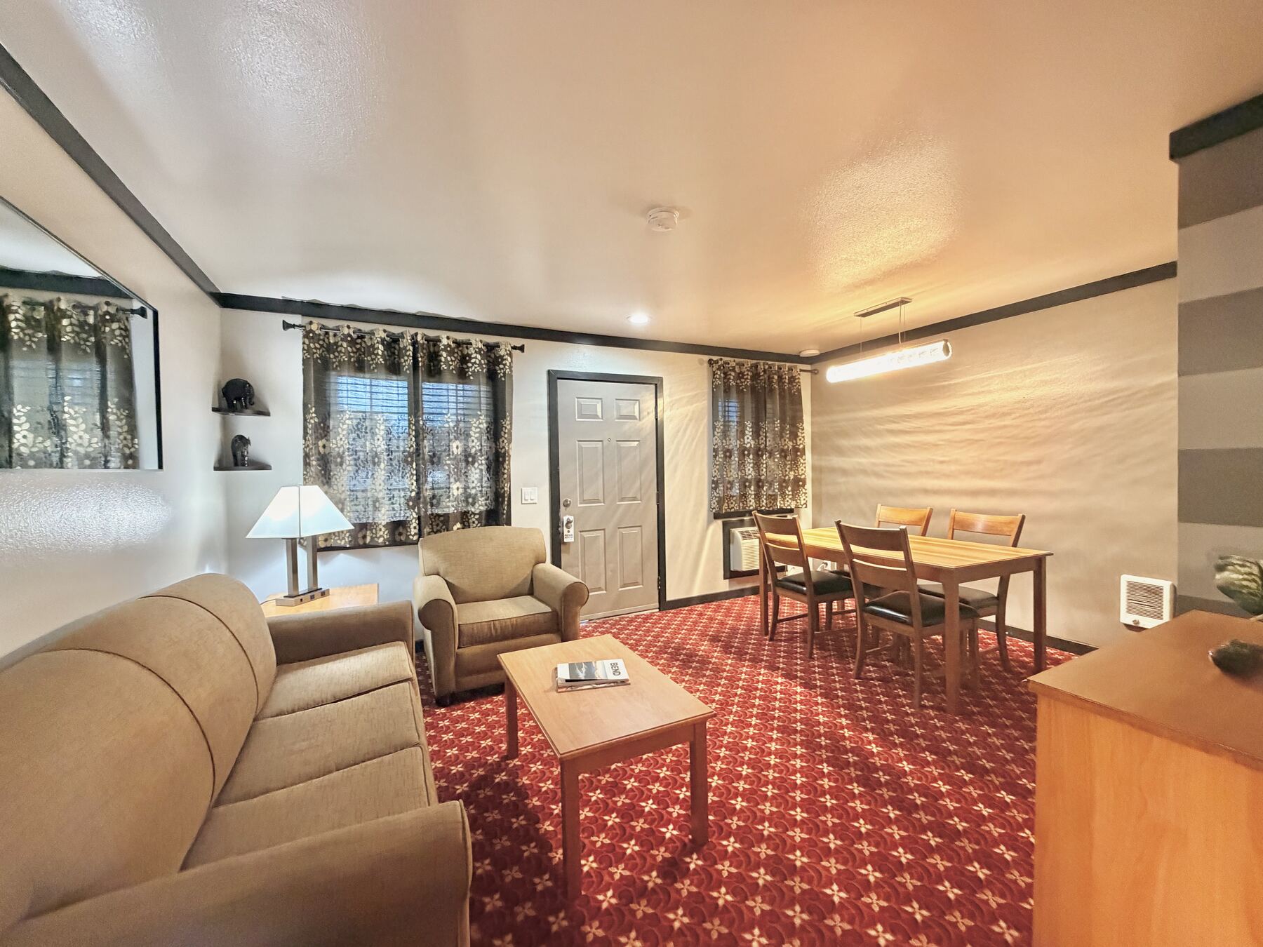 Sisters Queen Spa Suite living room with a sofa, armchair, coffee table, and dining table by the windows