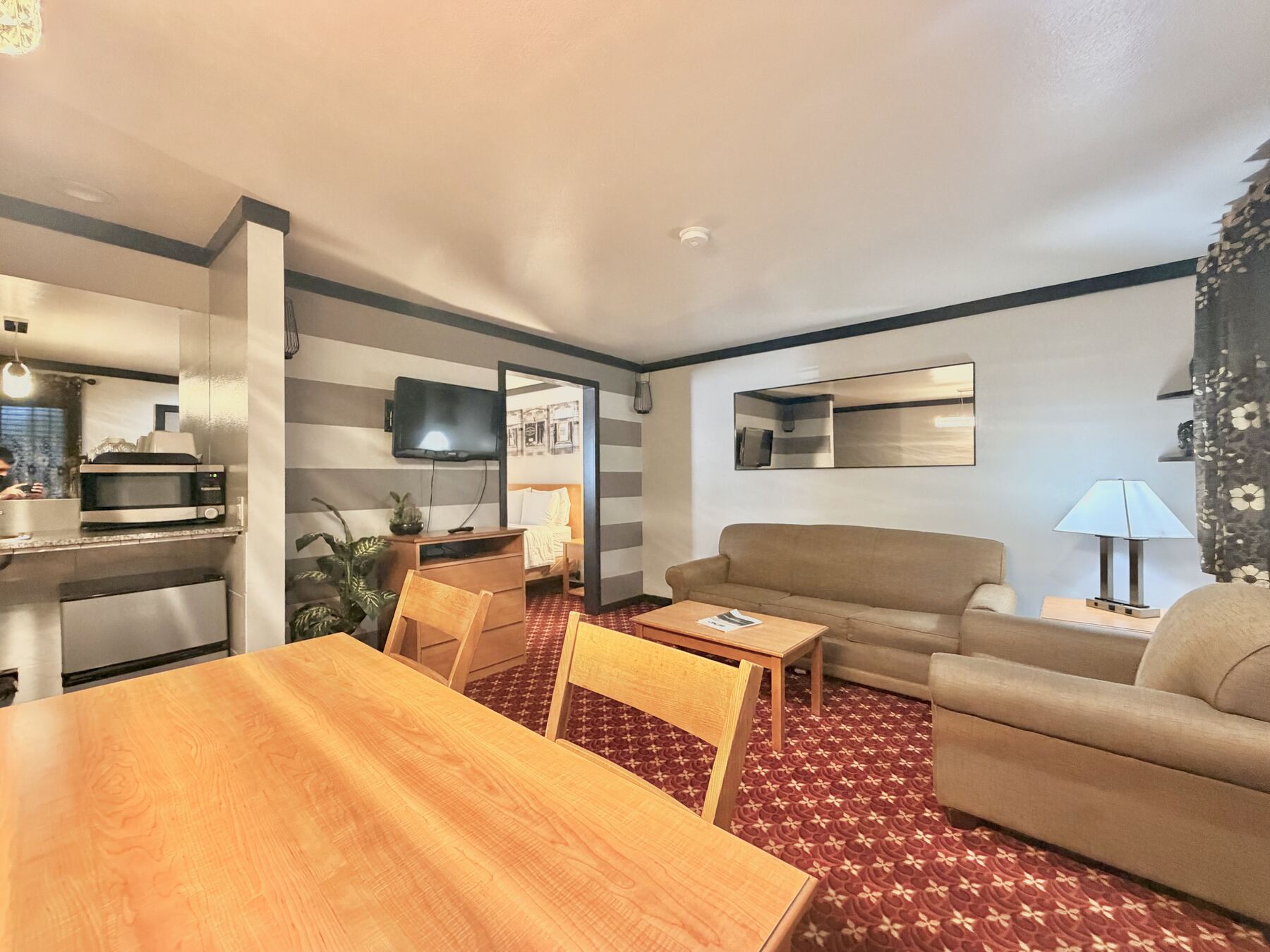Sisters Queen Spa Suite open layout from the dining table, showing the kitchenette, living room, and bedroom doorway