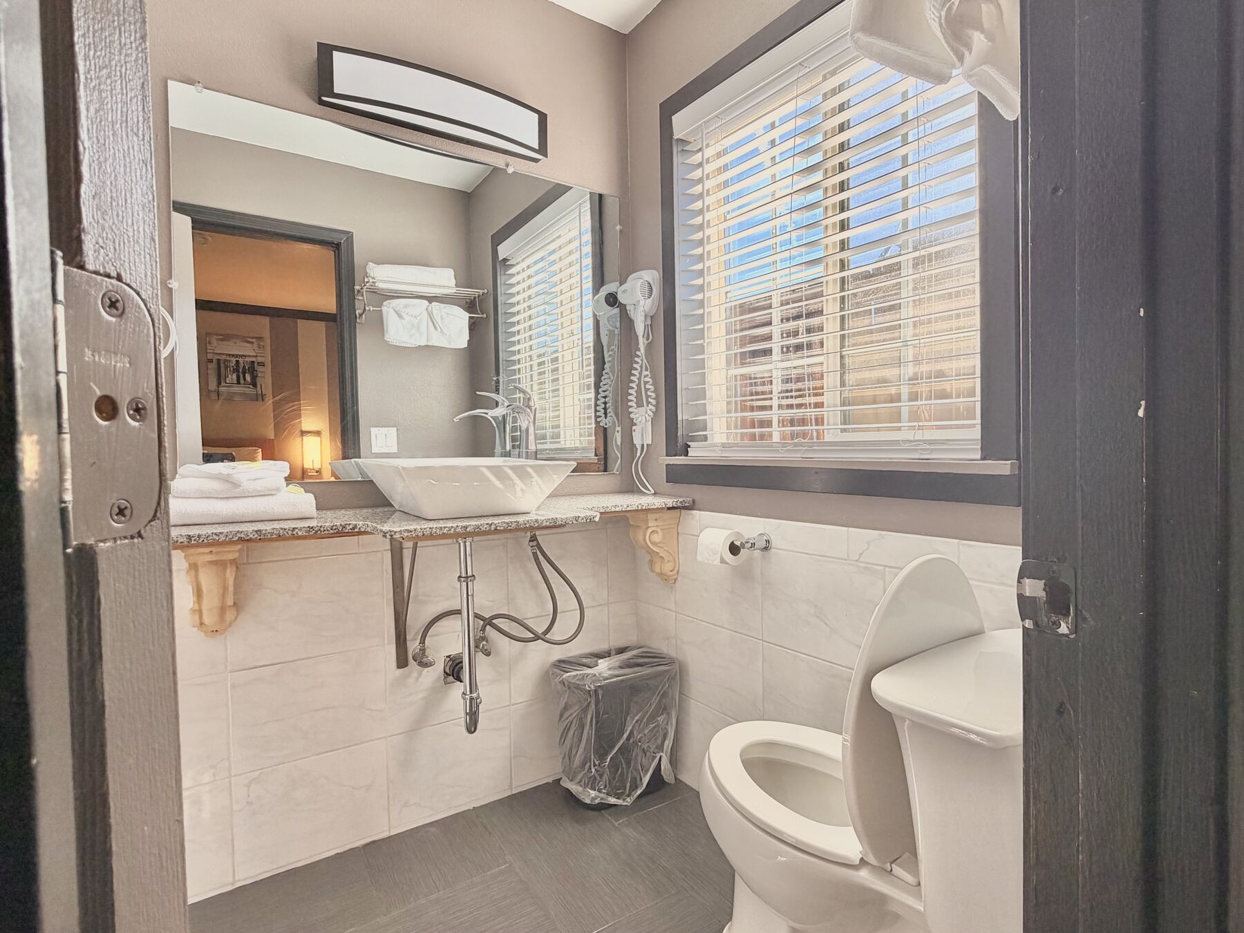 Spa suite bathroom with a vessel sink, lit mirror, hair dryer, and fresh towels